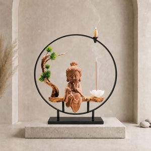 Bouddha brûleur d’encens Bulle Paisible avec tunique rose, structure circulaire noire, cône à reflux et bâton d’encens