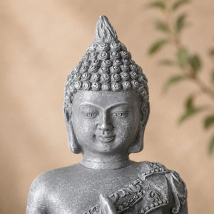 Gros plan sur le visage et la coiffure sculptée de la statuette Bouddha grise effet pierre