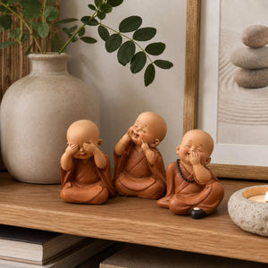 Trio de petits moines bouddhistes disposé sur une étagère en bois