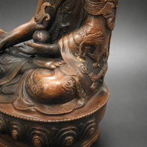 Gros plan sur les motifs de dragon et la finition vieillie de la statuette Bouddha en cuivre et laiton