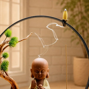 Gros plan du brûleur d’encens Bouddha Bulle Paisible sable avec cône à reflux et fumée dans un décor zen.