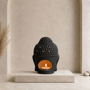 Diffuseur de parfum Bouddha en céramique décliné en noir et en blanc en action avec une bougie