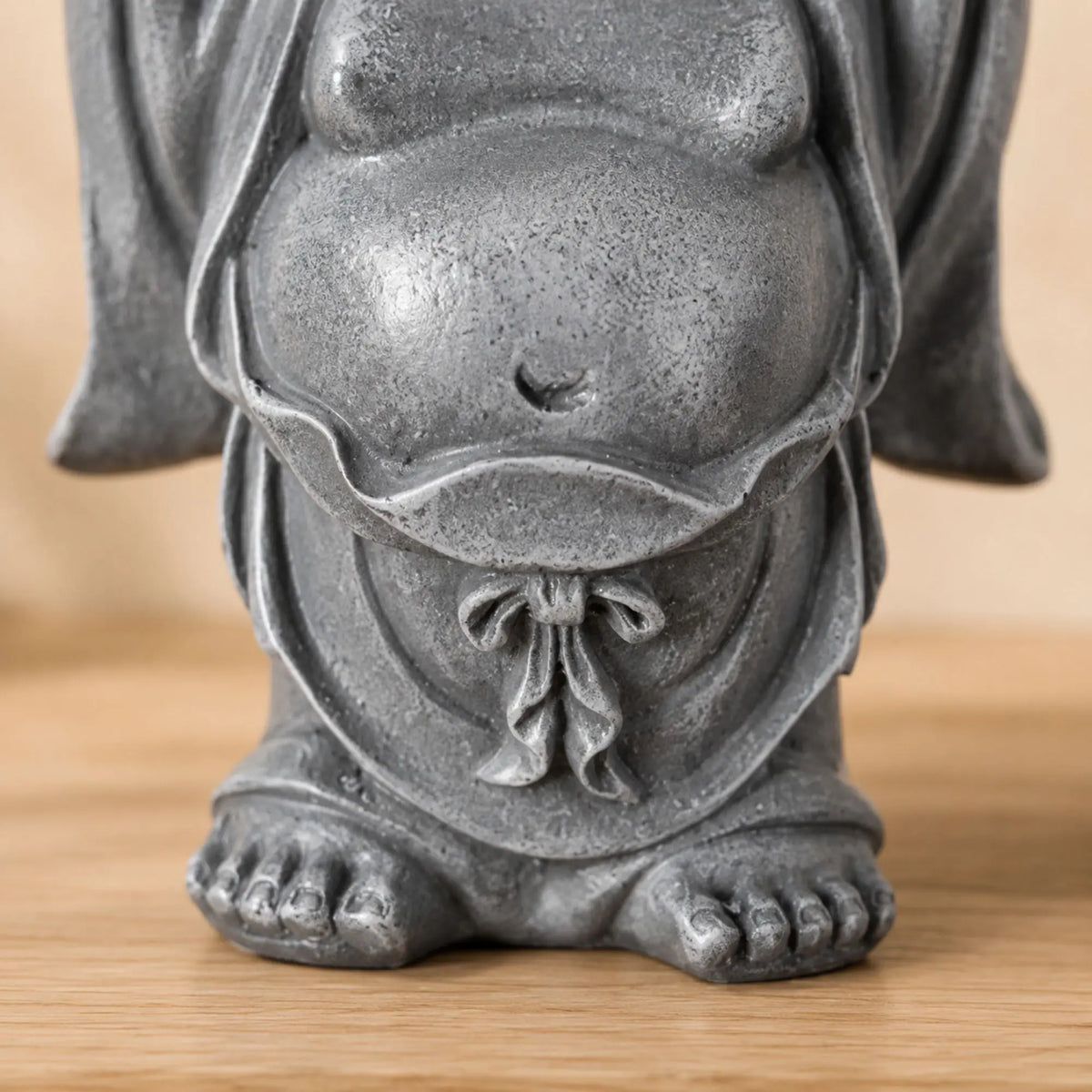 Gros plan sur le ventre, la robe et la finition de la statuette Bouddha rieur Budai en résine grise