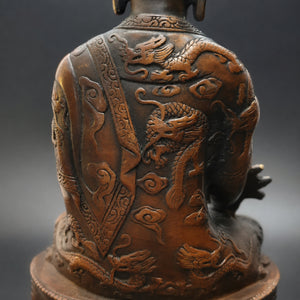 Détail des dragons en relief sculptés au dos de la statuette Bouddha assis en cuivre et laiton